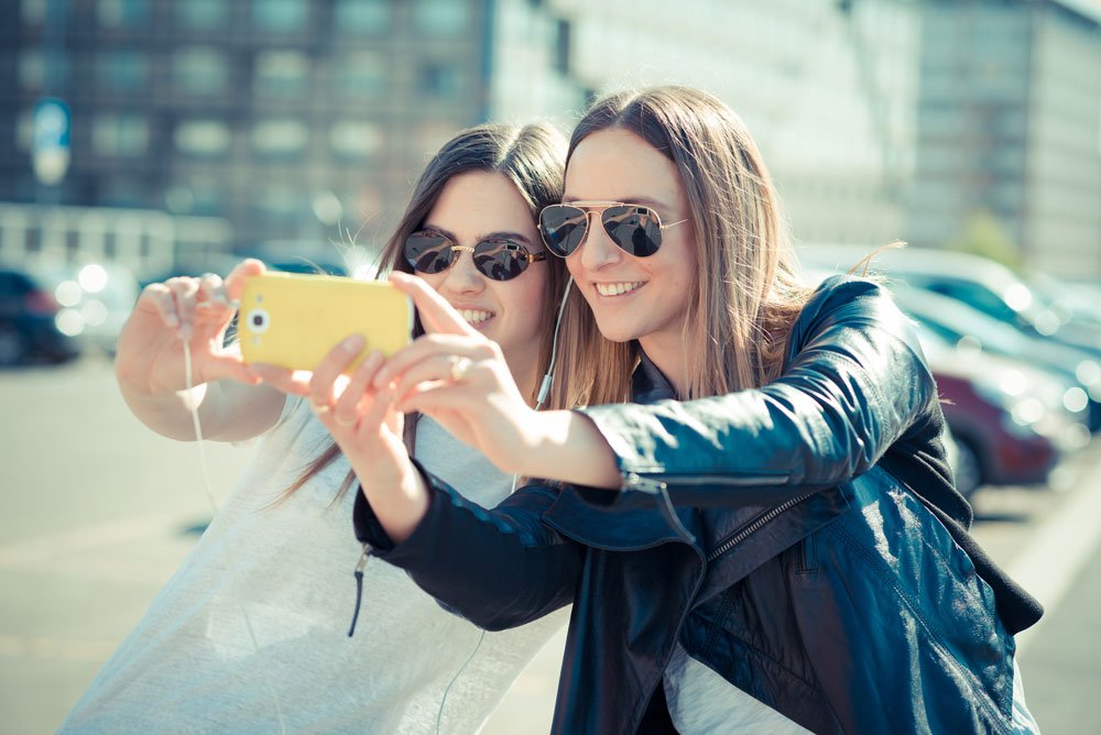 2 girls taking selfie on phone