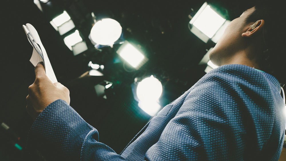 presenter reading a script on stage