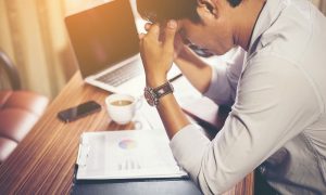 worried and anxious presenter sitting with head in hands at computer