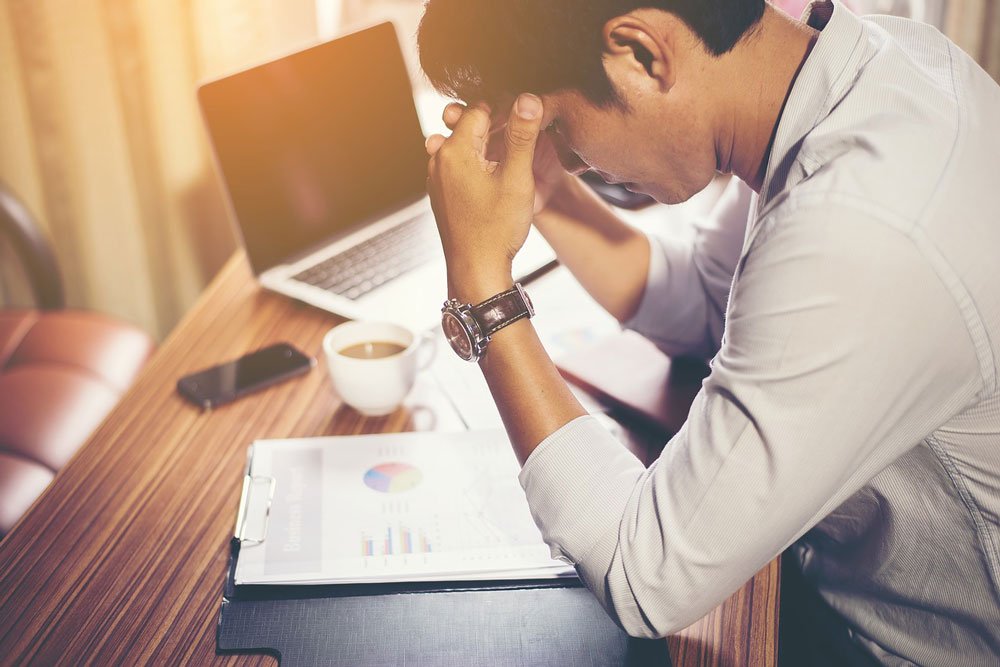 worried and anxious presenter sitting with head in hands at computer