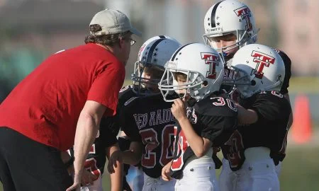 Footbal coach talking to group of young players