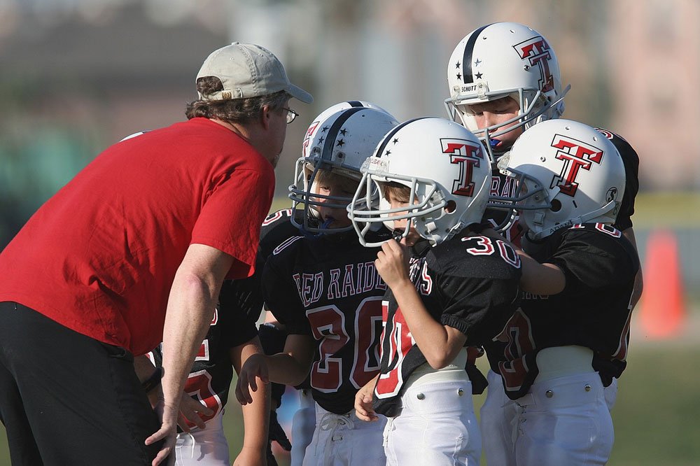 Footbal coach talking to group of young players