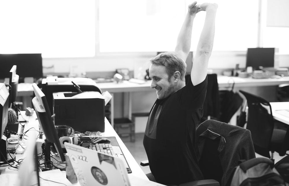 presentation designer stretching at desk