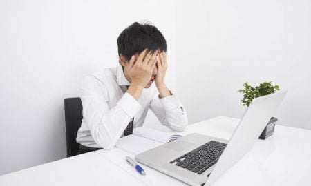 frustrated powerpoint user with head in hands looking at laptop