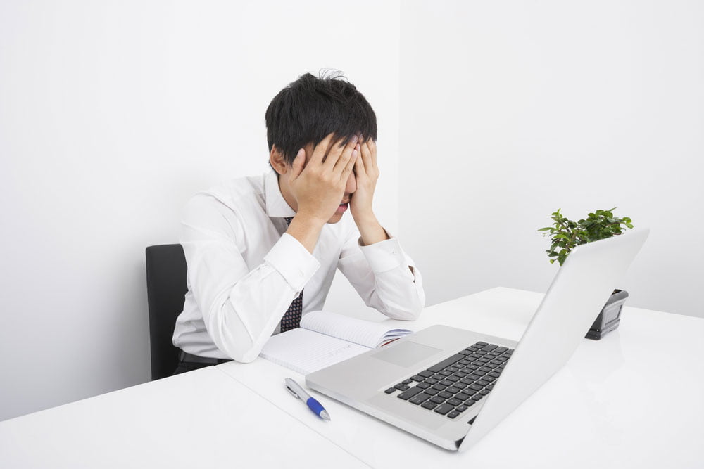 frustrated powerpoint user with head in hands looking at laptop