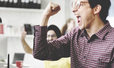 man cheering at computer screen