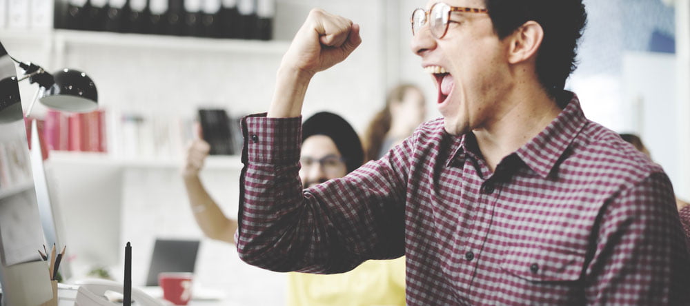 man cheering at computer screen