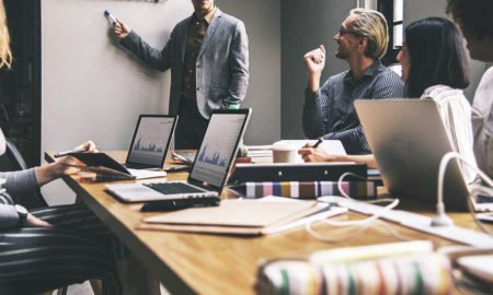 male presenter standing by screen in front of millennial business audience