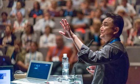 male presenter addressing large audience at scientific conference