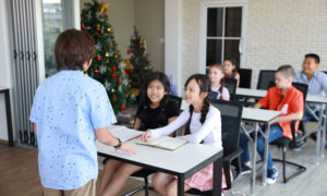 young boy in blue shirt speaking in front of class