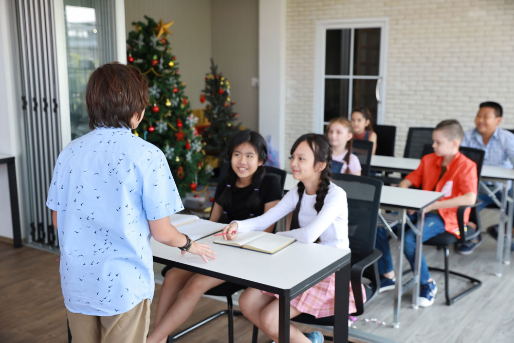 young boy in blue shirt speaking in front of class